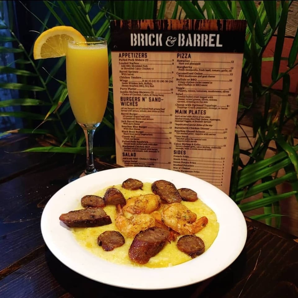 Cajun Shrimp & Grits with andouille sausage, a mimosa, and a Brick & Barrel menu.
